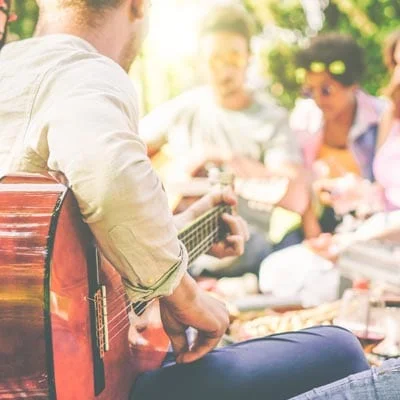 gathering of friends at a barbecue, one playing guitar